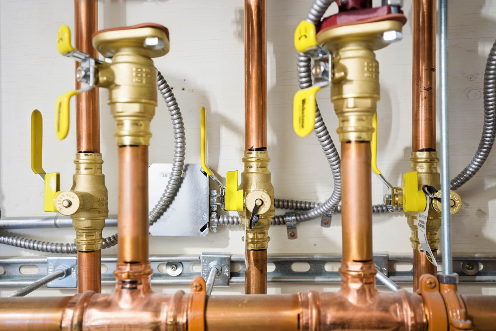 Copper manifold close-up with yellow gas/isolation valves - new construction plumbing
