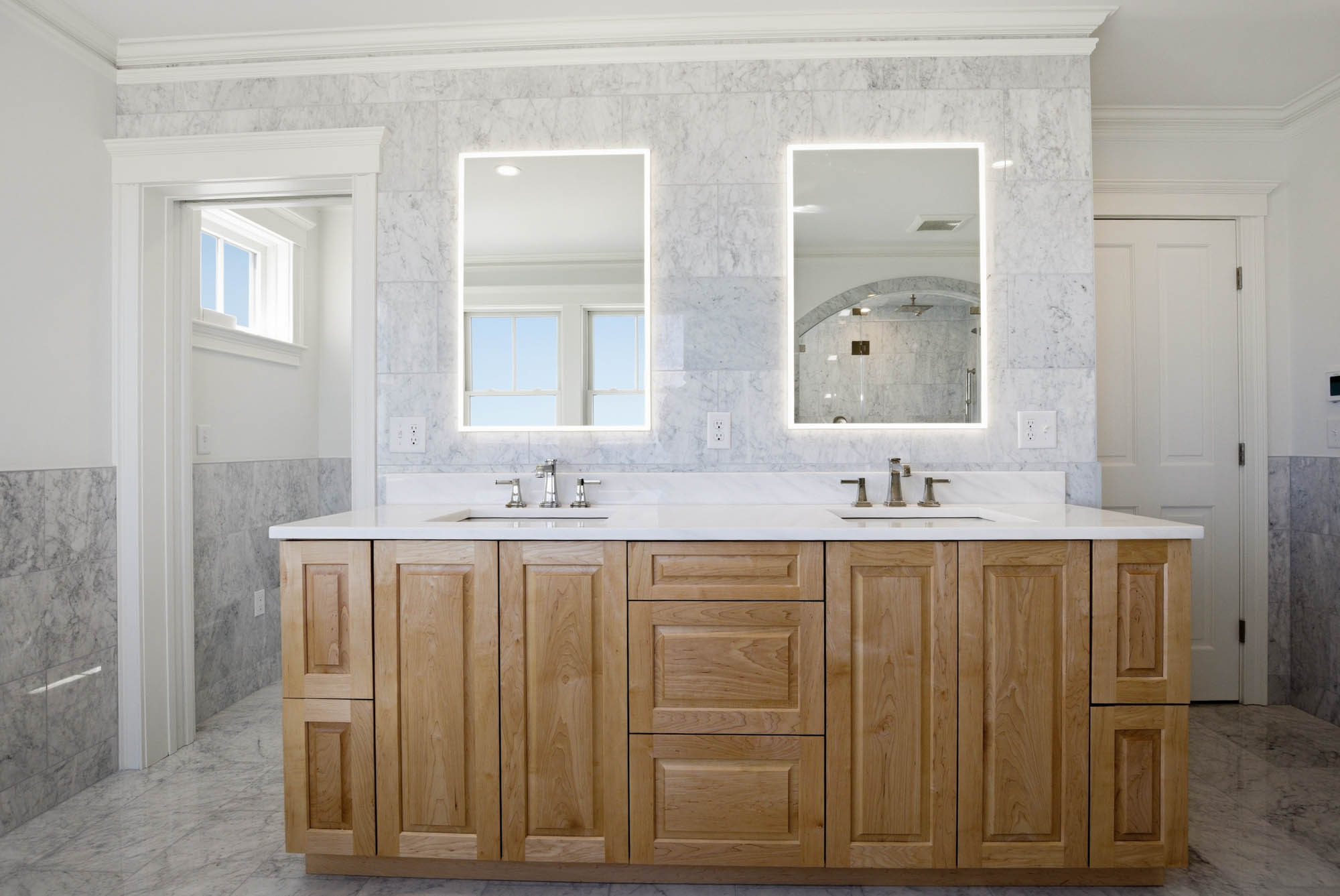 Double vanity with LED backlit mirrors and marble backsplash - bathroom renovation plumbing