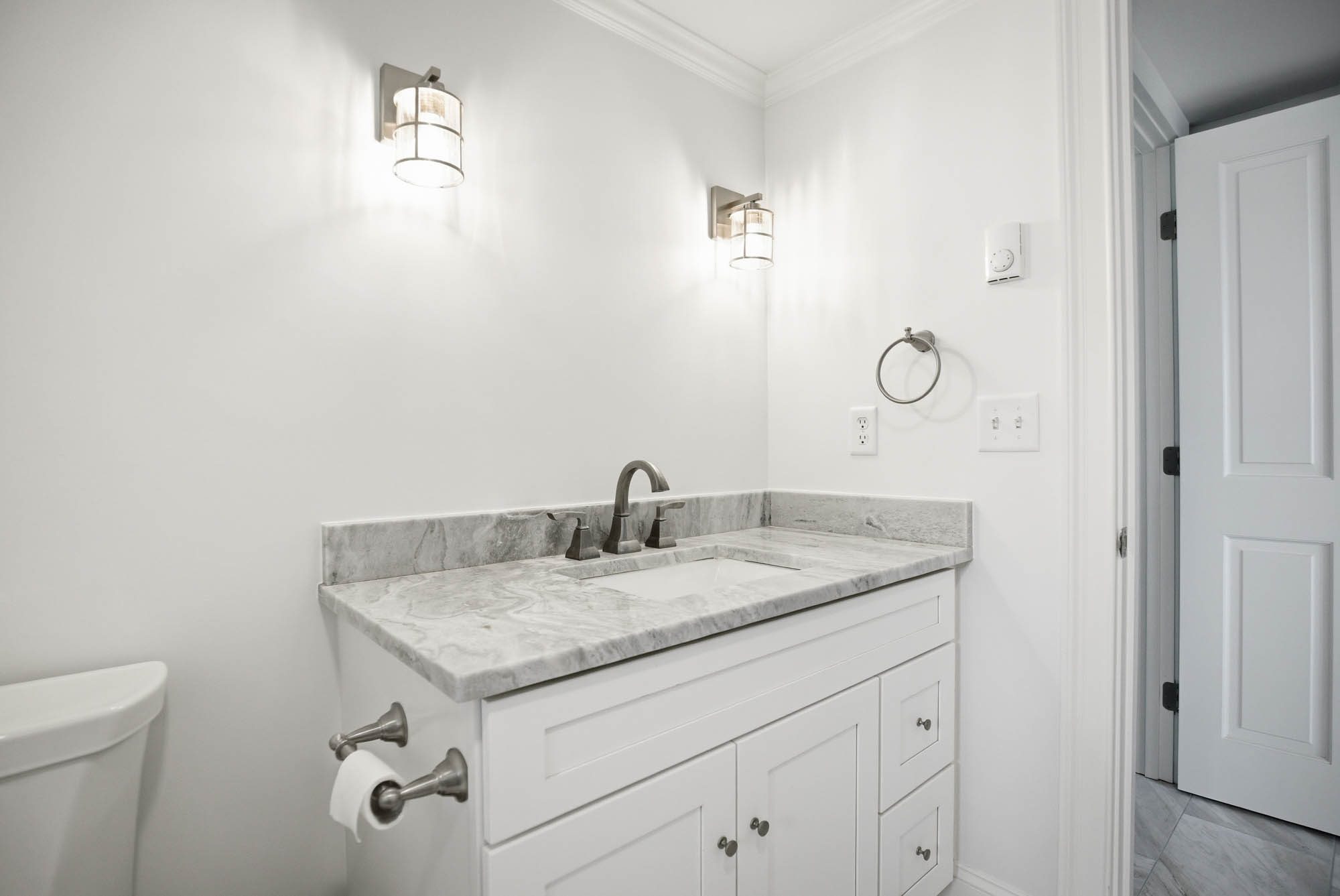 Guest bathroom with white vanity, grey marble top, cage sconce lighting - Ipswich MA plumbing project