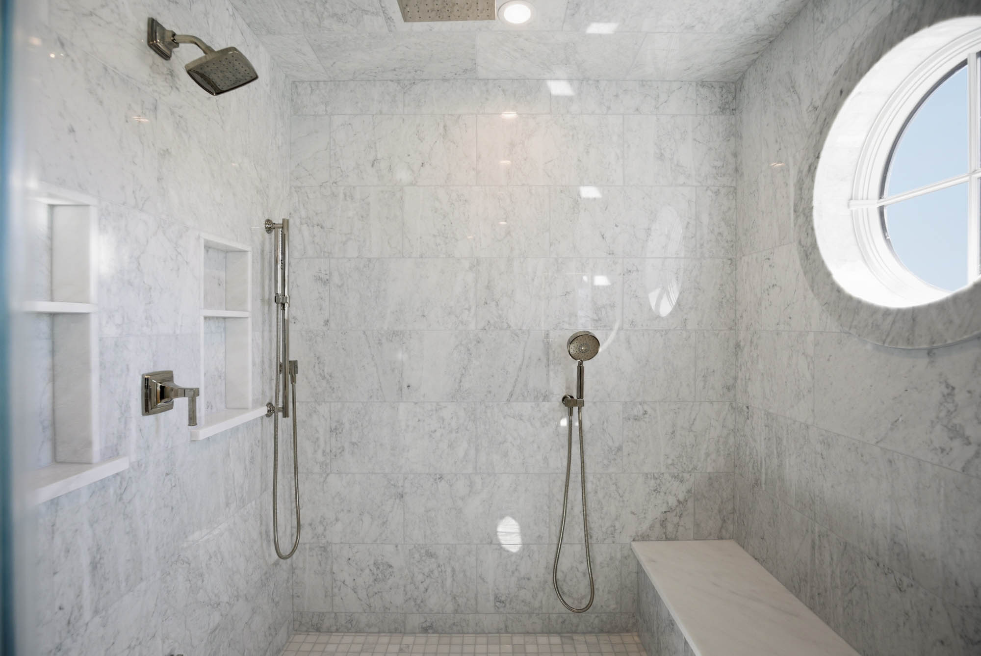 Large Carrara marble walk-in shower interior with porthole window - Newburyport MA plumbing project