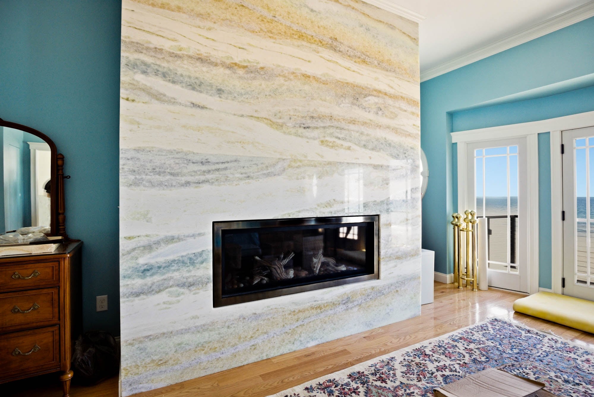 Linear gas fireplace with marble slab surround, ocean view through French doors - Essex County MA