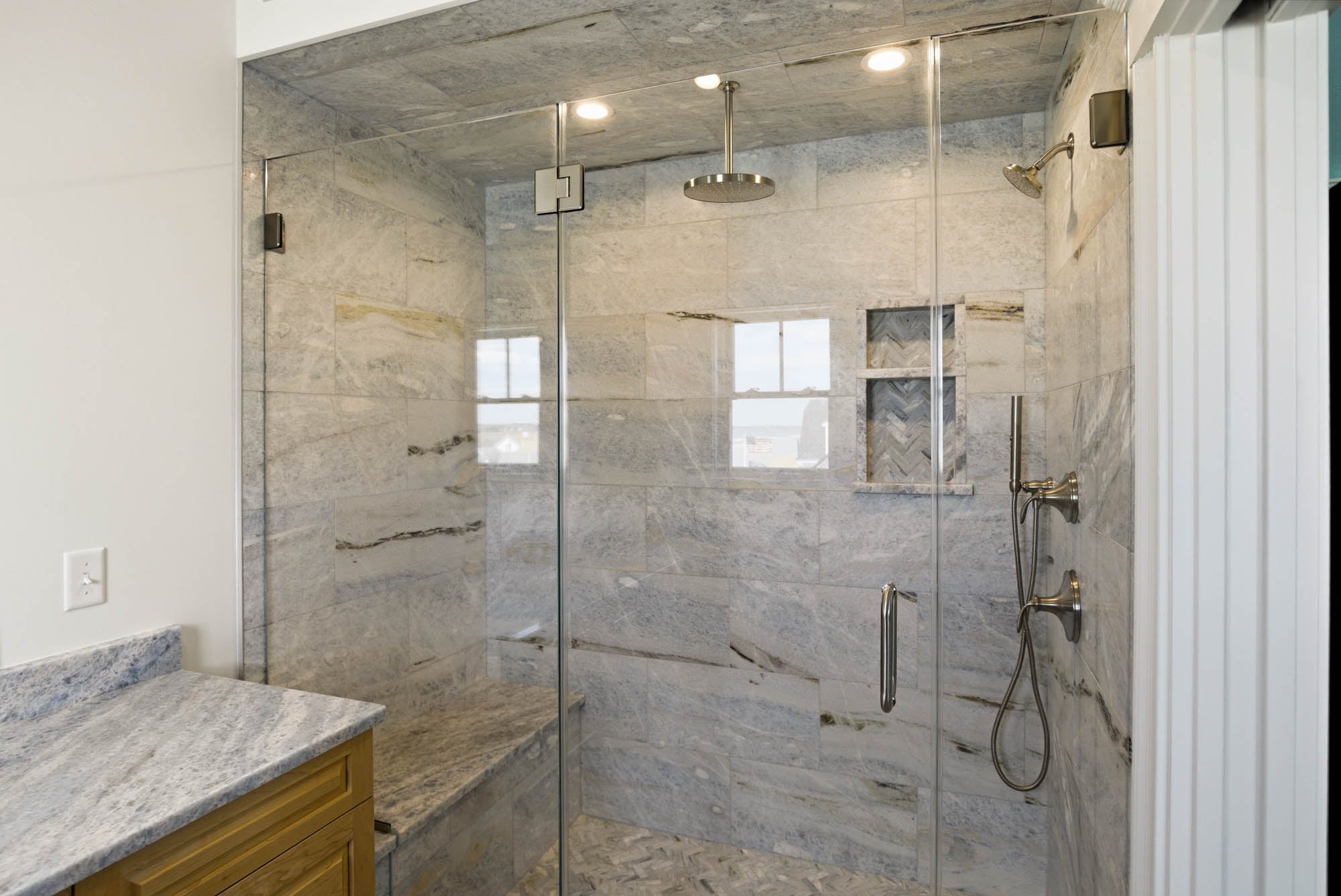 Wide glass-enclosed marble shower with bench seat, rainfall + dual shower heads - Essex County MA