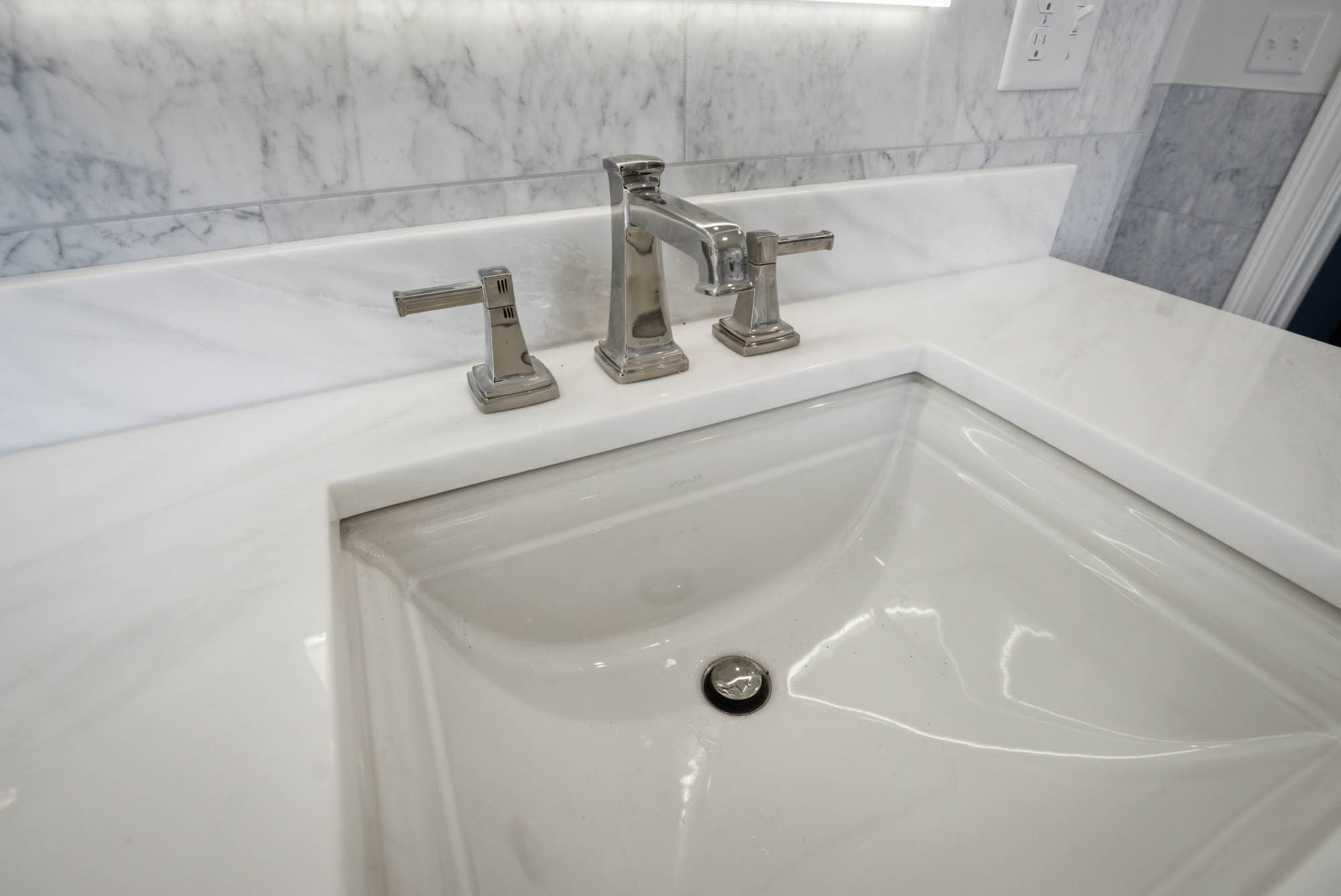 Close-up of polished chrome widespread vanity faucet on white marble - Essex County MA