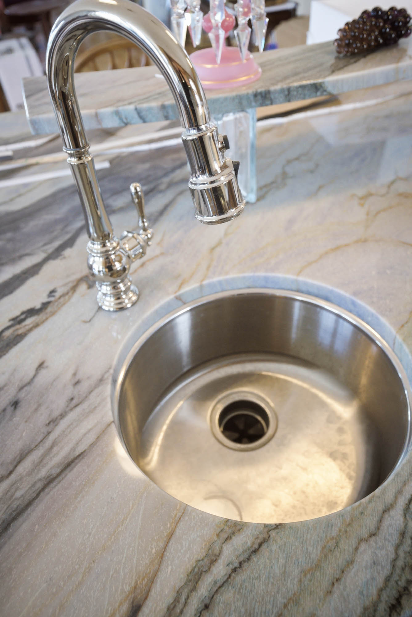 Round stainless bar sink with pull-down faucet on dramatic marble waterfall island - kitchen plumbing