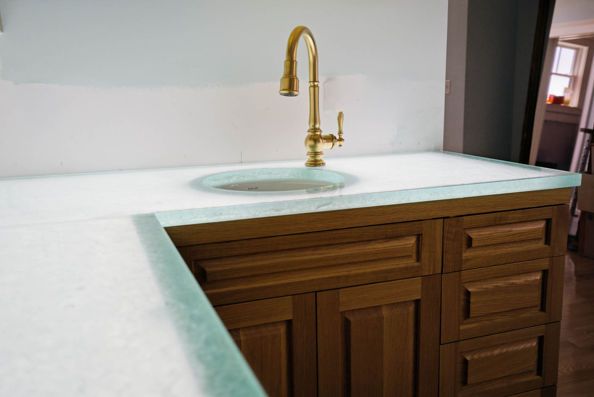 Wet bar with glass counter, oval Kohler bar sink, brass bridge faucet - kitchen plumbing